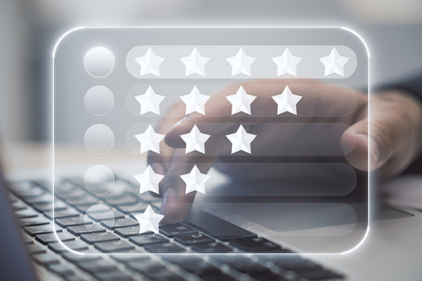 Giving customer feedback concept with digital display with star ratings on hand typing on laptop keyboard background